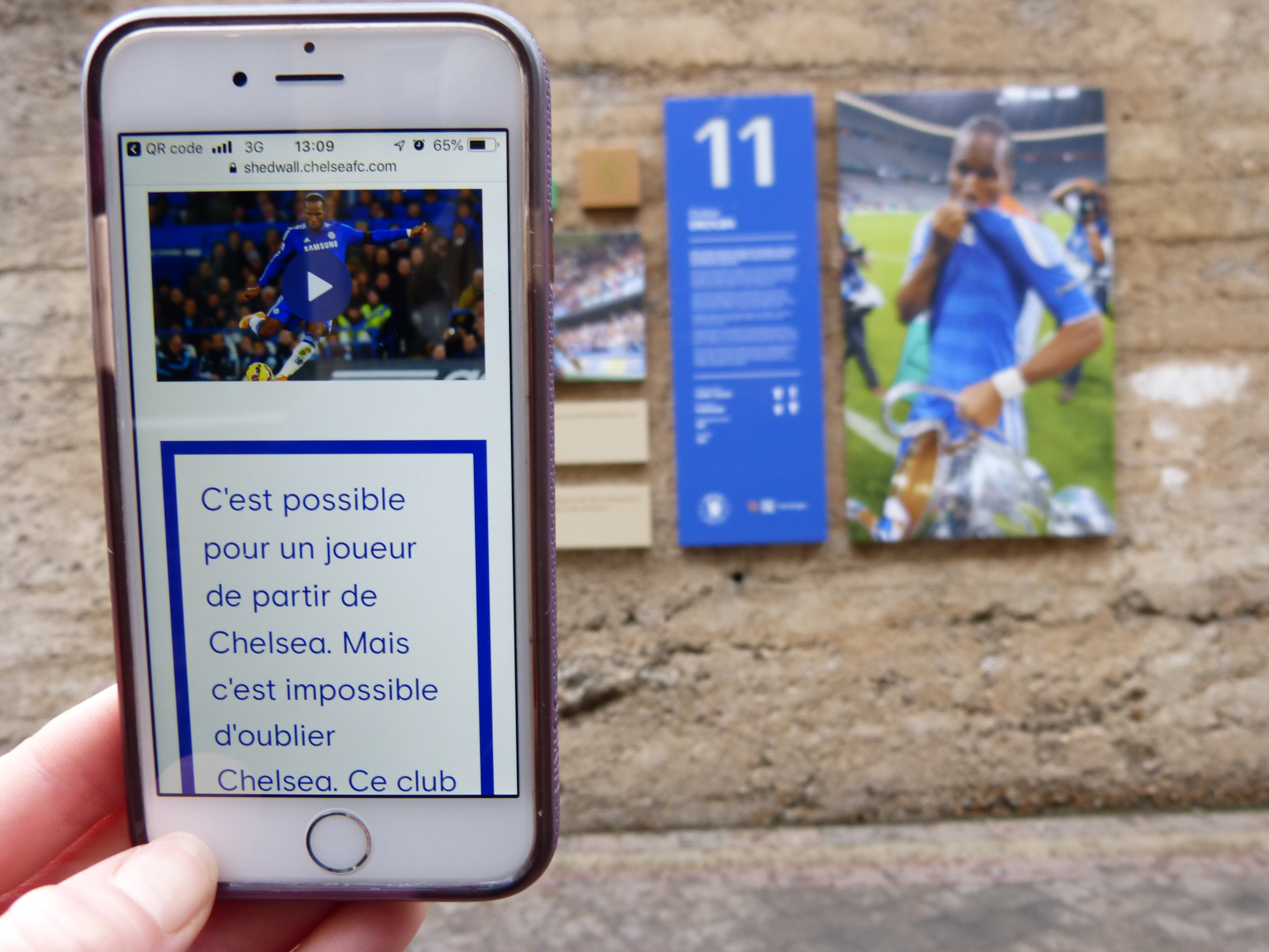 P1090426 Chelsea Shed Wall mobile website viewed through mobile phone alongside physical imagery displayed at Stamford Bridge stadium